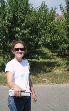 Carolyn in front of her peach orchards. Always smiling!
